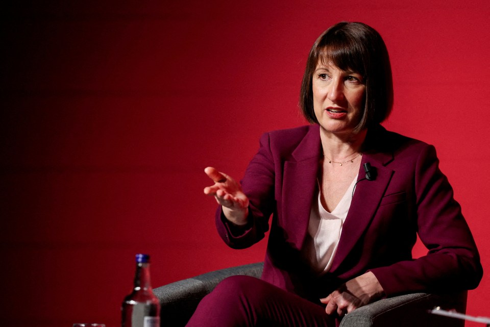 a woman in a purple suit sits in front of a red wall