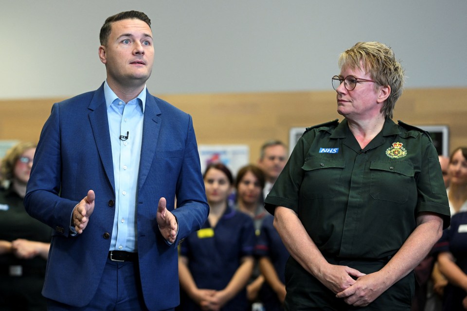 a man in a blue suit stands next to a woman in a green uniform that says nhs