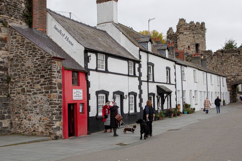 people walking a dog in front of the smallest house