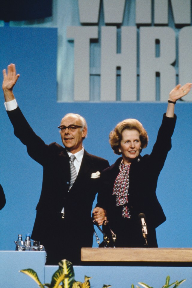 a man and woman are waving in front of a sign that says win thru