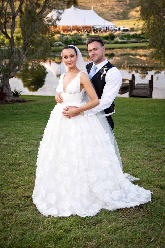 a bride and groom pose for a picture in front of a lake