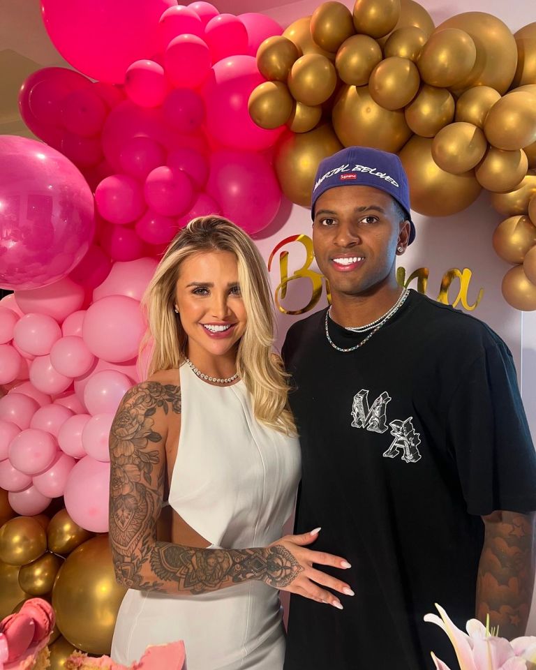 a man and a woman are posing for a picture in front of pink and gold balloons