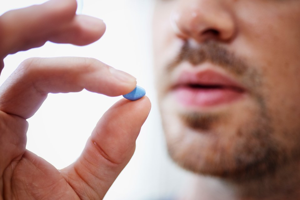 a man is holding a blue pill in his hand