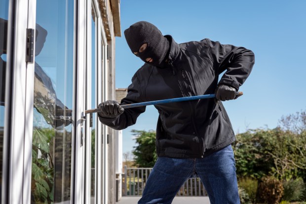 a man wearing a mask and gloves is trying to break into a house