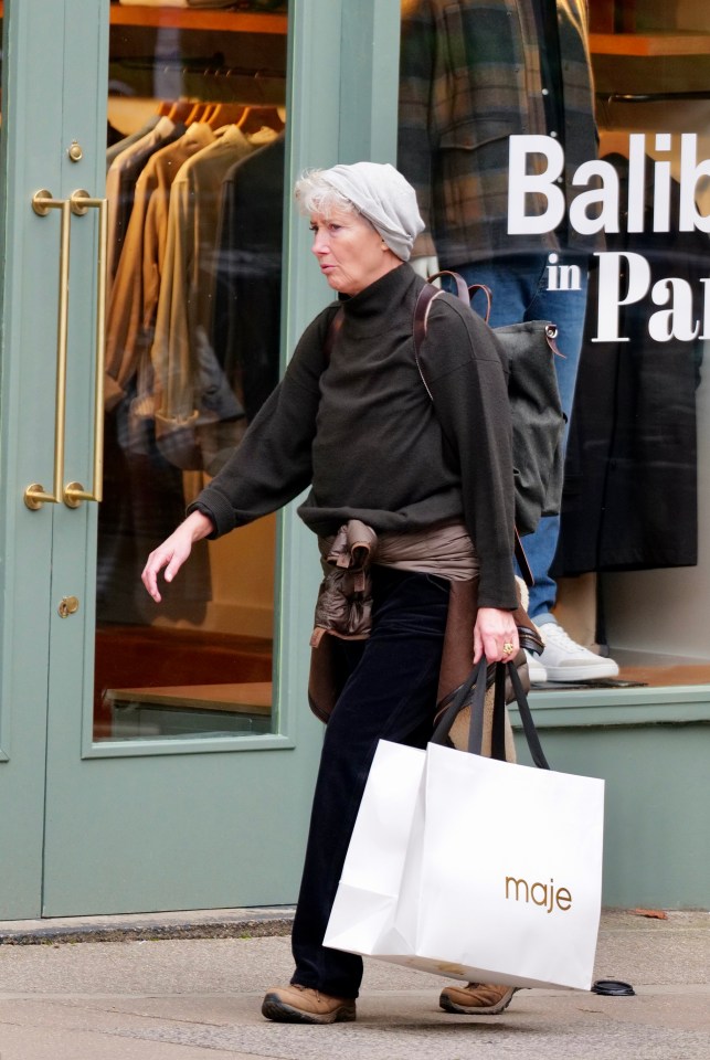 a woman carrying a maje shopping bag walks past a store