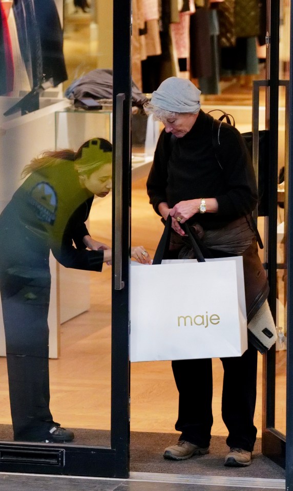 a woman is holding a maje shopping bag