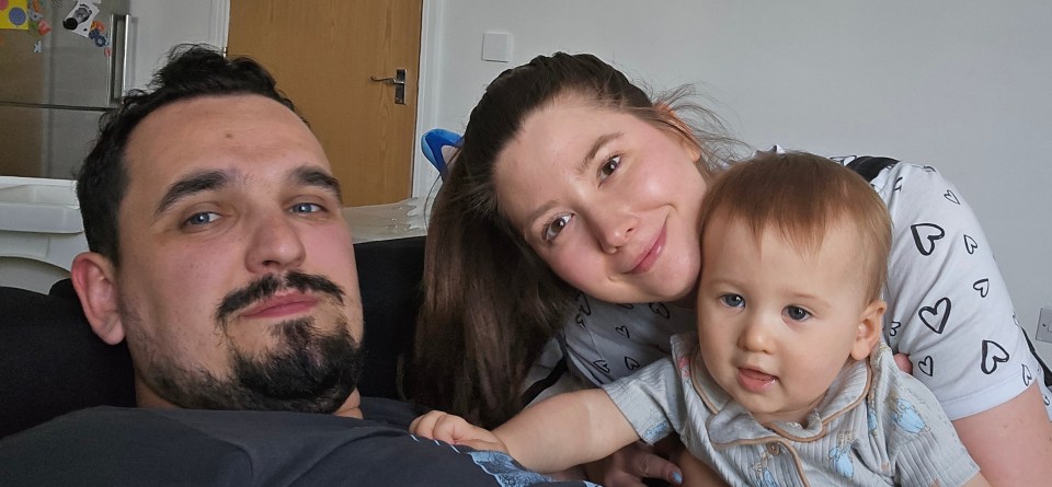 a man and woman holding a baby with hearts on their shirts