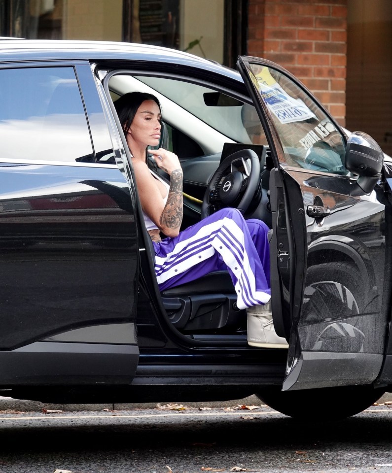 a woman sits in a black car with the door open