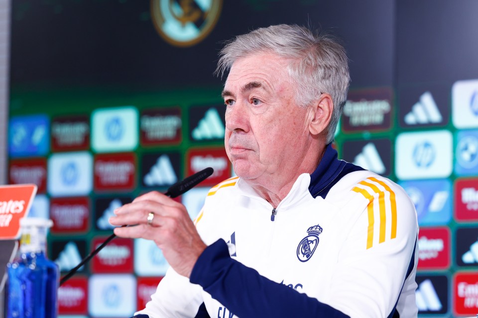 a man in a real madrid jacket talks into a microphone