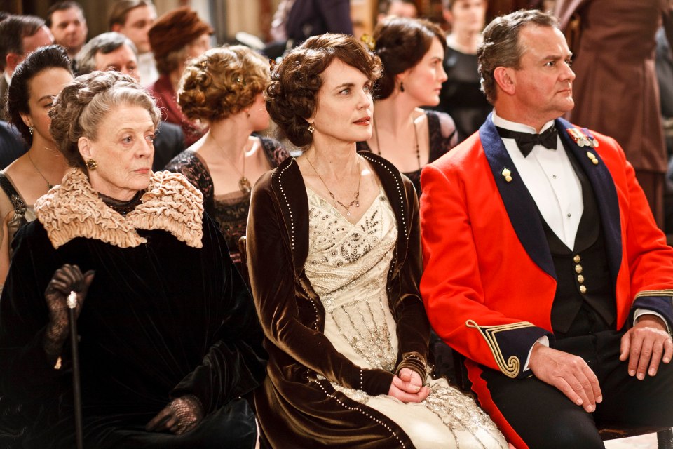 a man in a red tuxedo sits next to a woman in a white dress