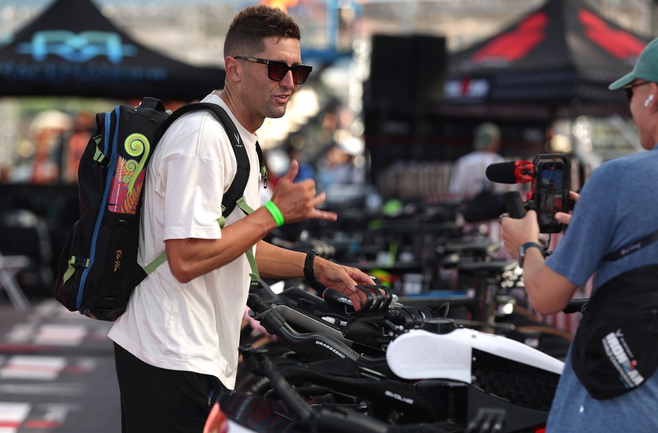 a man wearing sunglasses and a backpack talks to another man