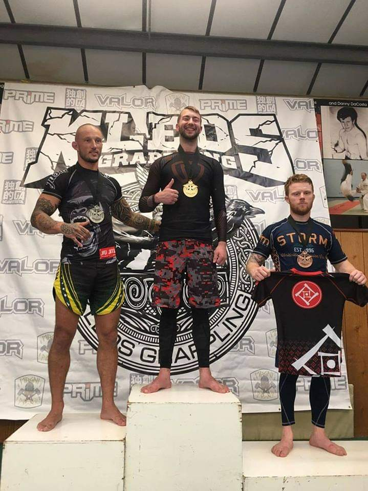 three men standing on a podium with one wearing a storm shirt