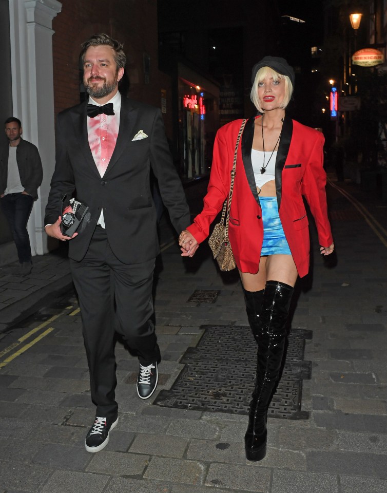 a man in a tuxedo holds hands with a woman in a red jacket