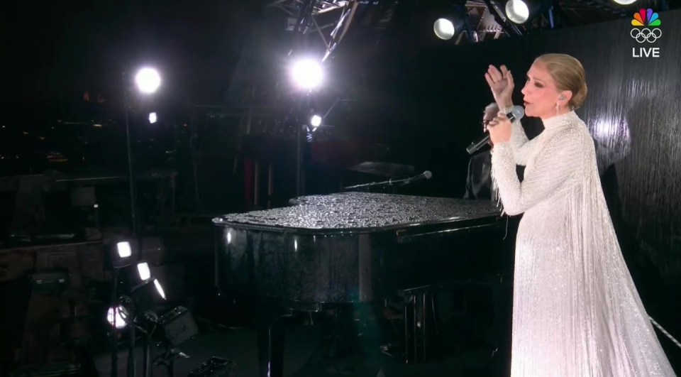 a woman in a white dress sings into a microphone in front of a piano