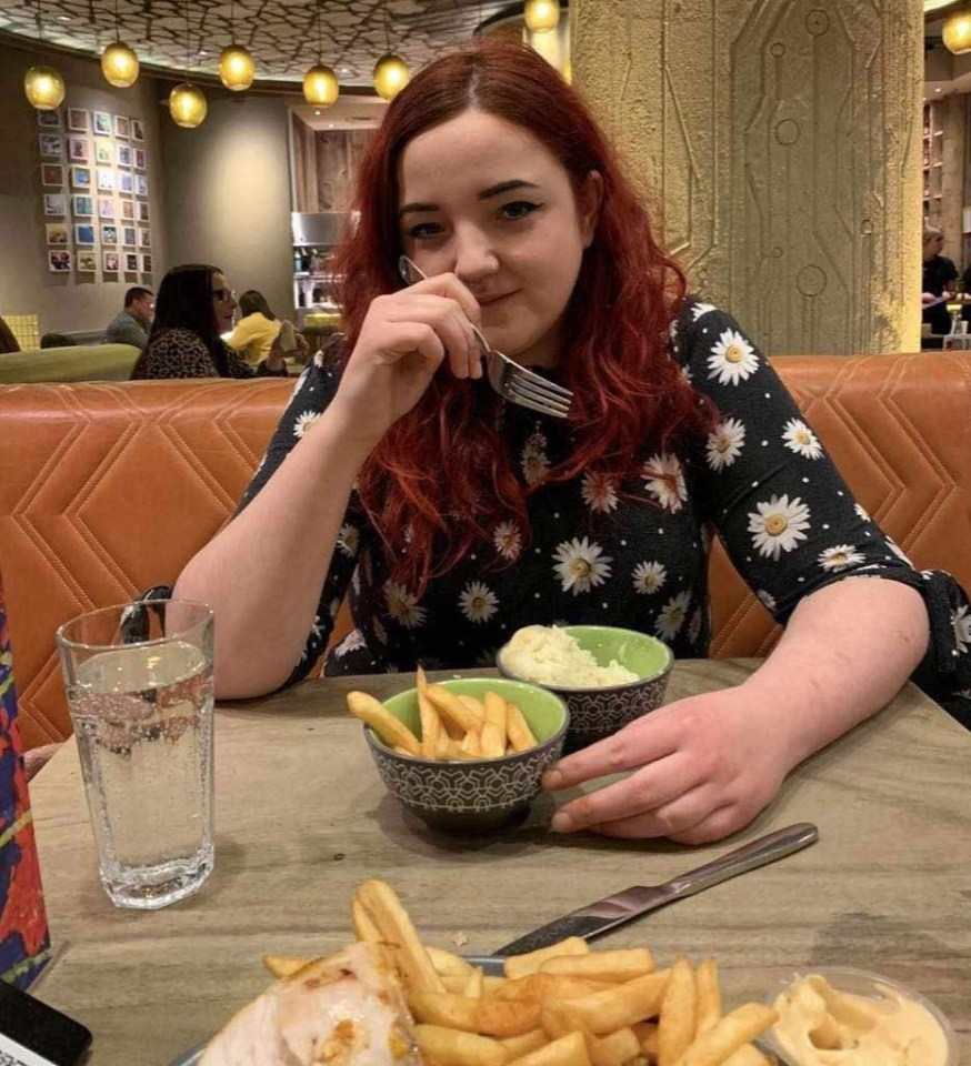 a woman with red hair is sitting at a table eating french fries