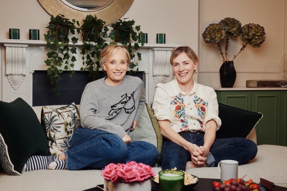 two women are sitting on a couch and one has a horse on her sweater