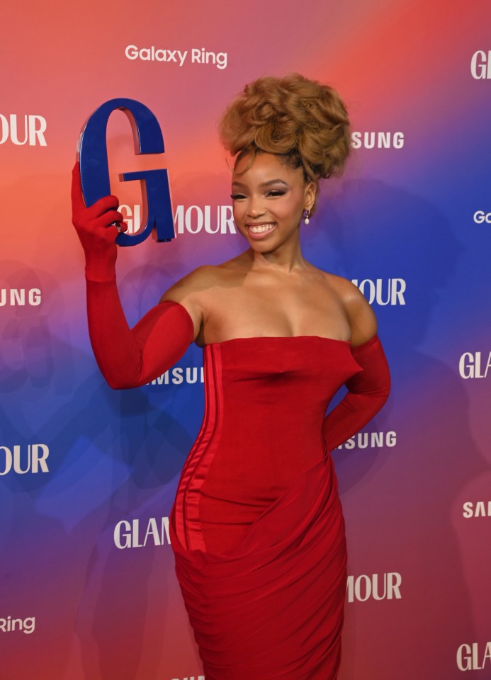 a woman in a red dress and red gloves holds a blue g