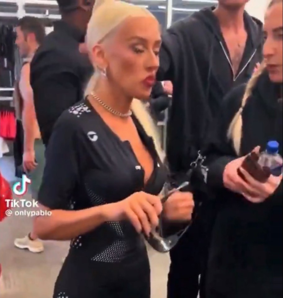 a woman in a black dress is standing in a crowd holding a bottle of water .