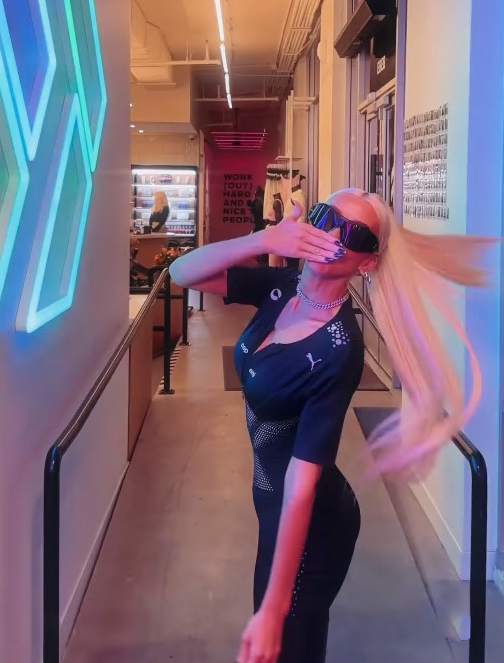 a woman covering her face in front of a sign that says work hard have a nice time