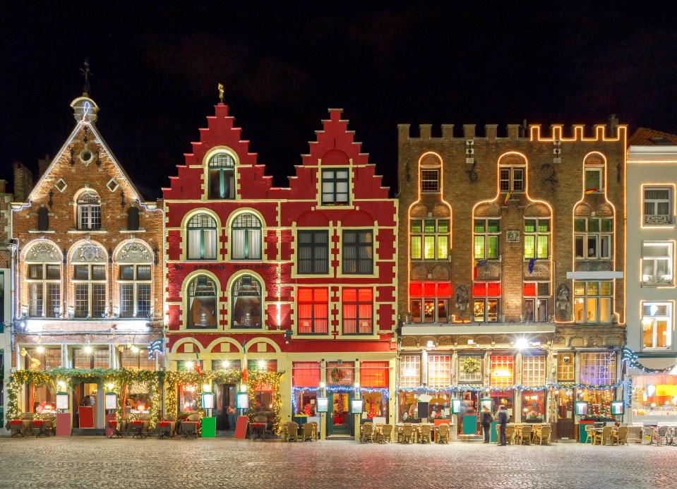 a row of buildings are lit up with christmas lights