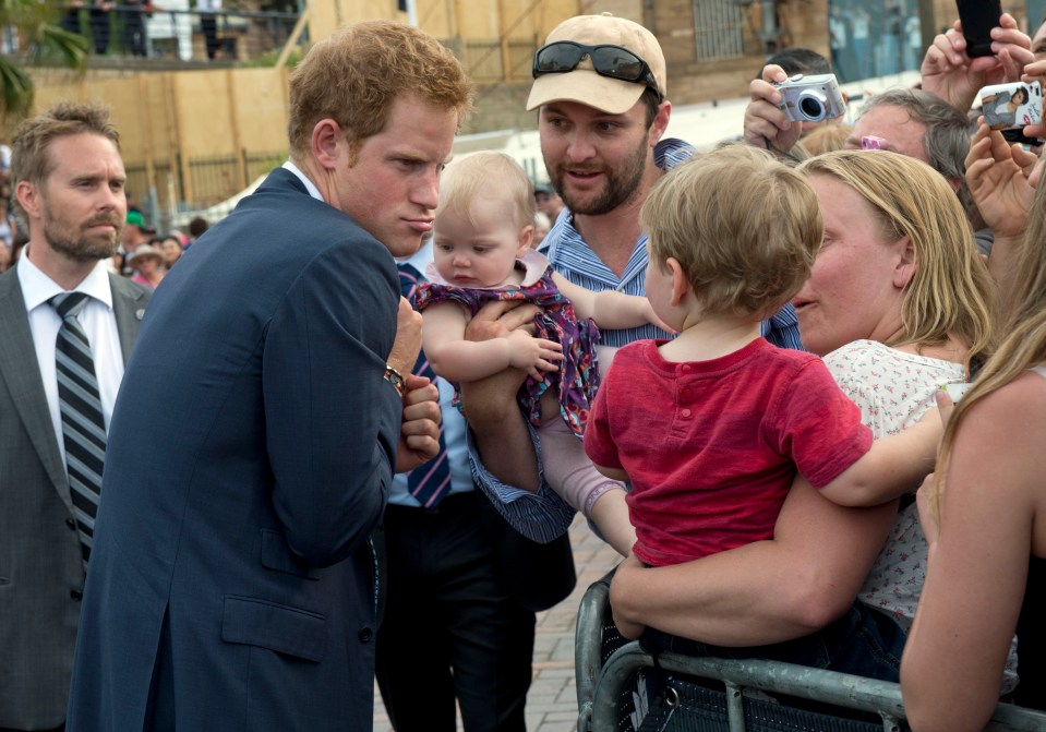 a man holding a baby while another man takes a picture