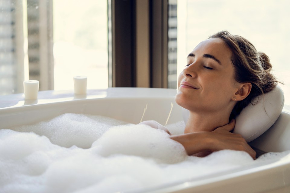 a woman is taking a bath with her eyes closed