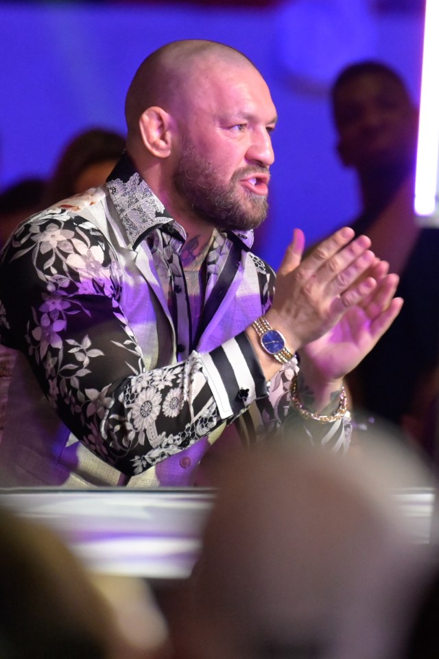 a man wearing a watch and a floral shirt applauds