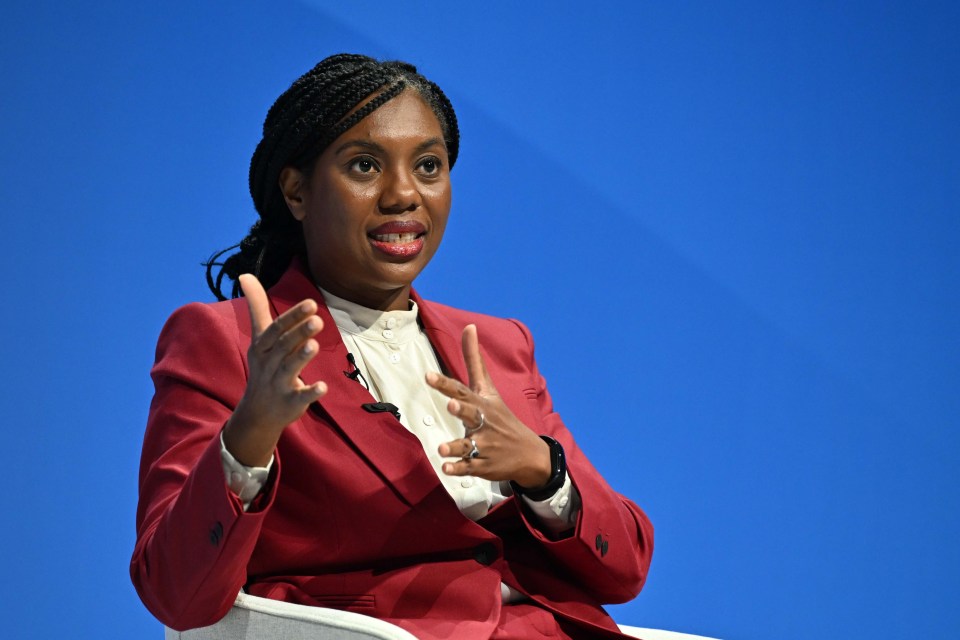 a woman in a red suit is sitting in front of a blue background