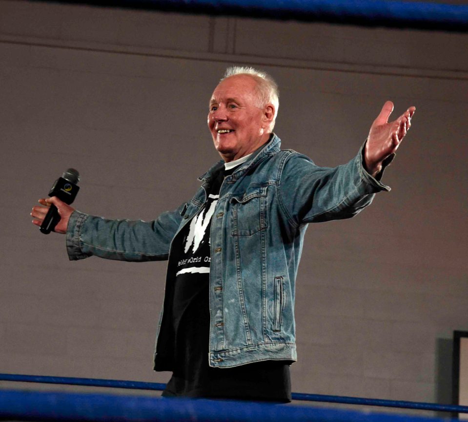 a man in a denim jacket holds a microphone in his hand