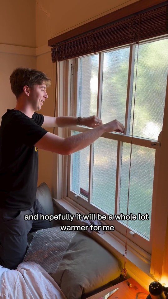 a man is looking out a window with a caption that says " hopefully it will be a whole lot warmer for me "