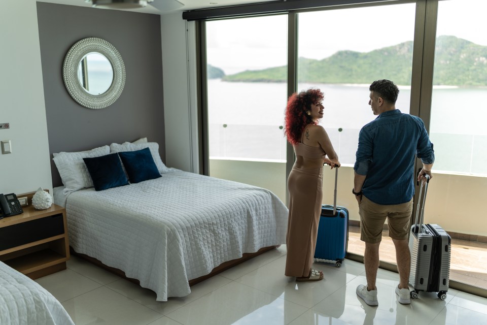 a man and a woman standing in a hotel room looking out a window