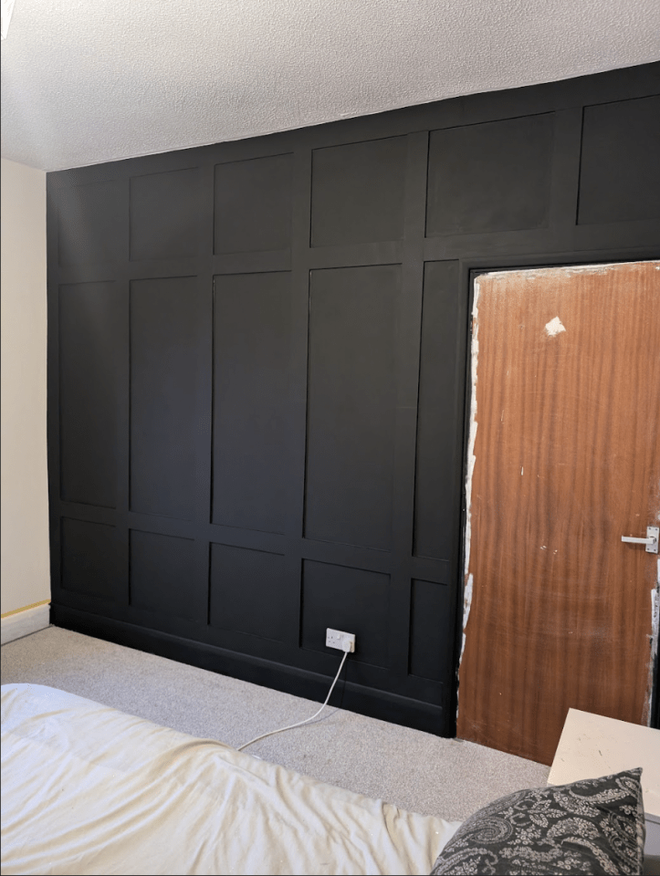 a bedroom with a black wall and a wooden door