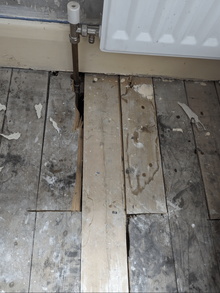 a dirty wooden floor next to a radiator