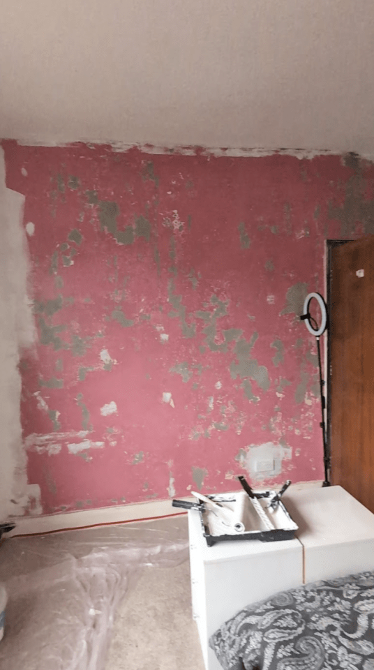 a pink wall is being painted in a bedroom