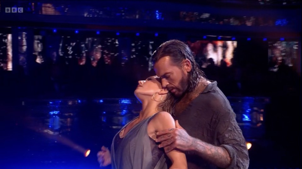 a man and woman are dancing in front of a bbc logo