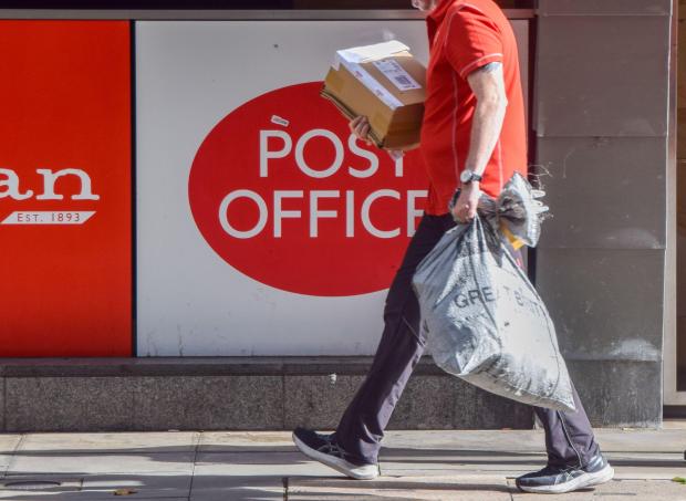 a man carrying a bag in front of a post office