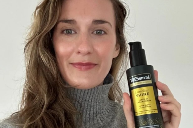 a woman in a grey sweater is holding a bottle of tresemme