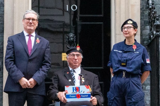 a man in a wheelchair holding a poppy appeal sign