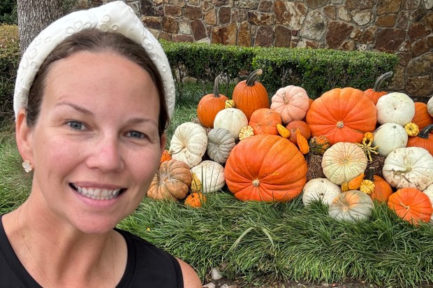 a woman standing in front of a pile of pumpkins wearing a black shirt that says ranch