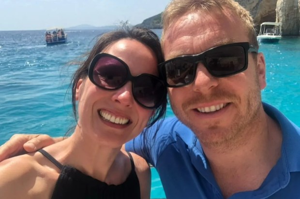 a man and a woman are posing for a picture with a boat in the background