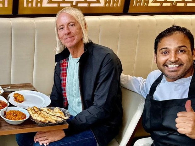 three men sit at a table with plates of food on it