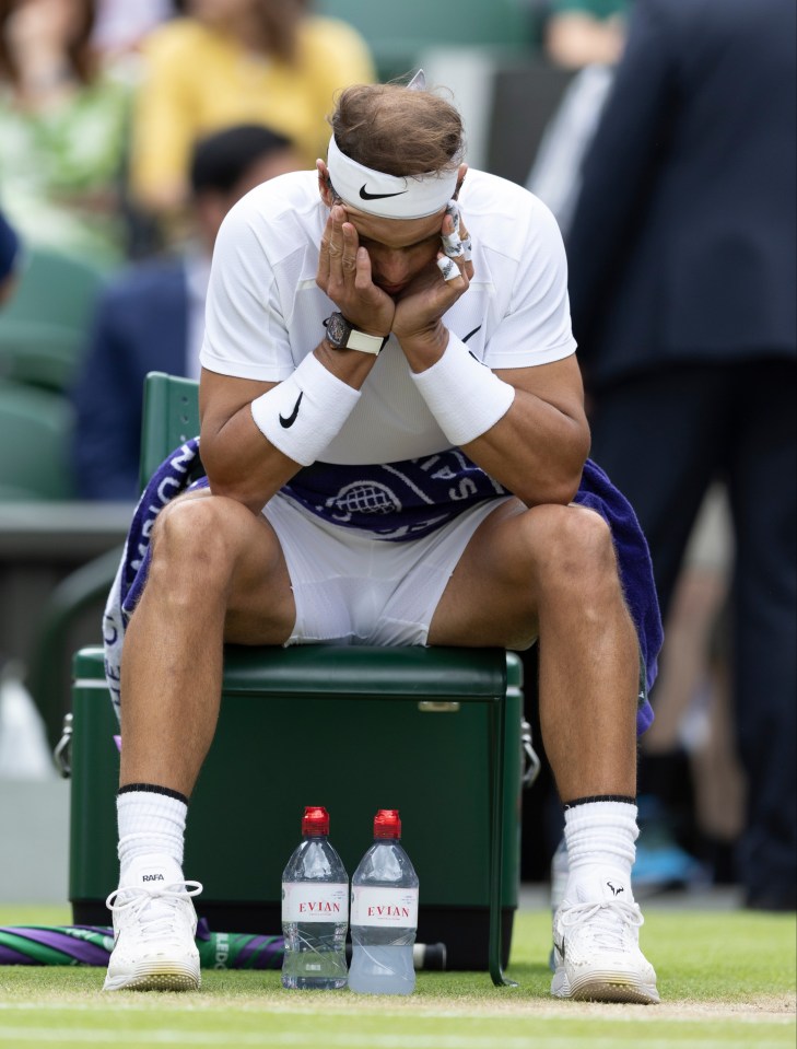 a tennis player sits on a bench next to two bottles of evian water