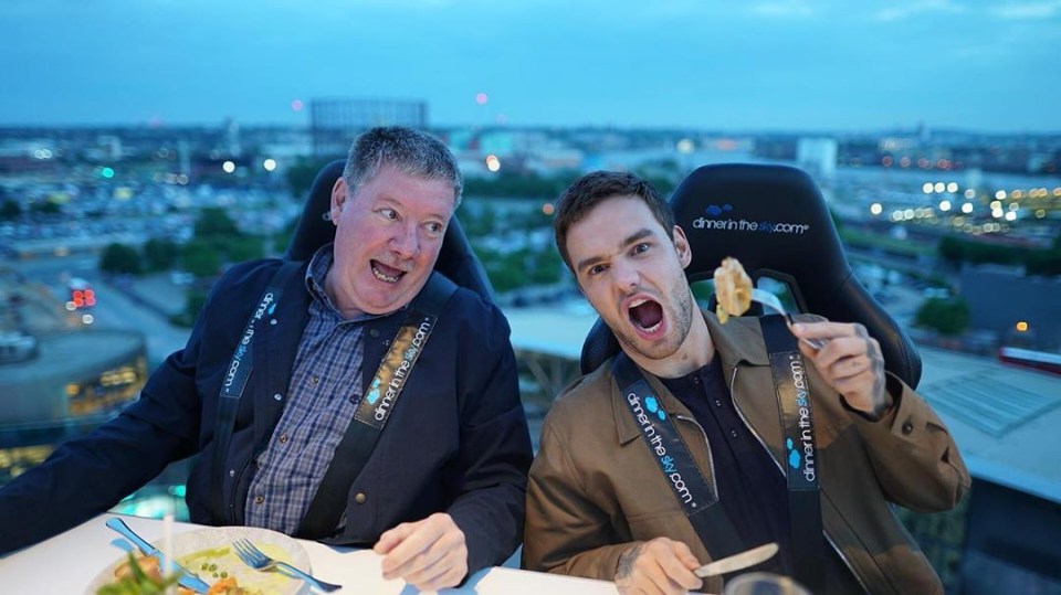 two men are eating food in a dining in the sky chair