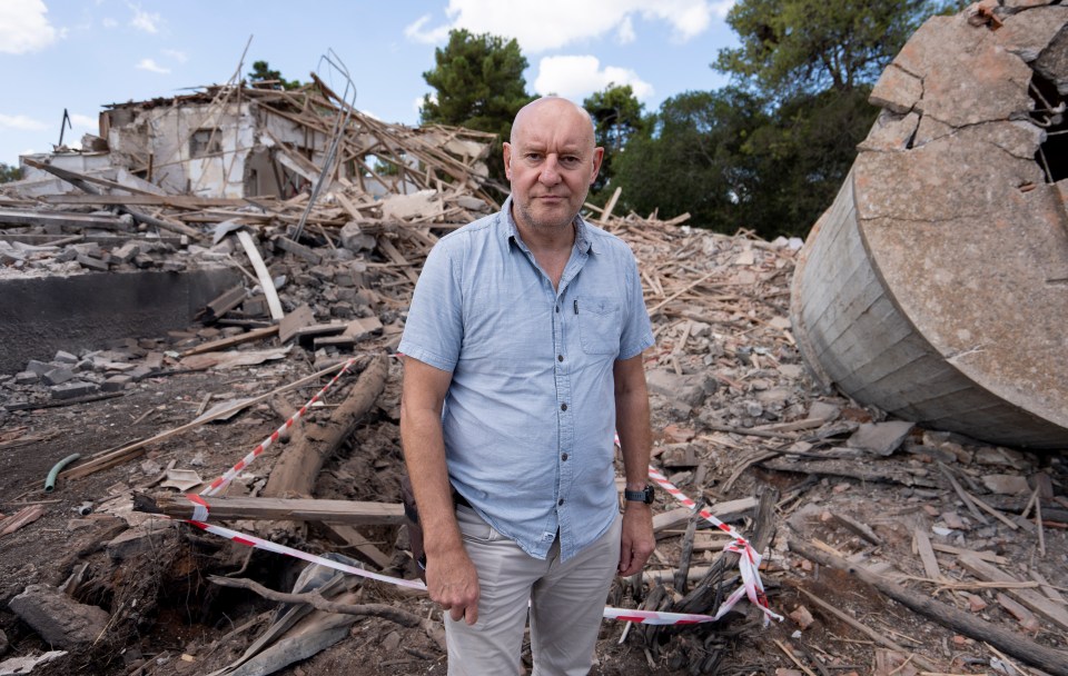 a man in a blue shirt stands in front of a pile of rubble