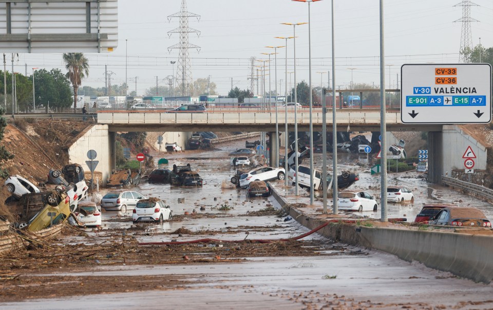 Damaged cars are seen along a destroyed road just outside Valencia