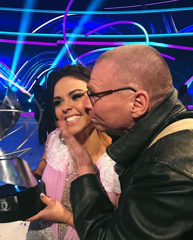 a man kisses a woman on the cheek while holding a trophy