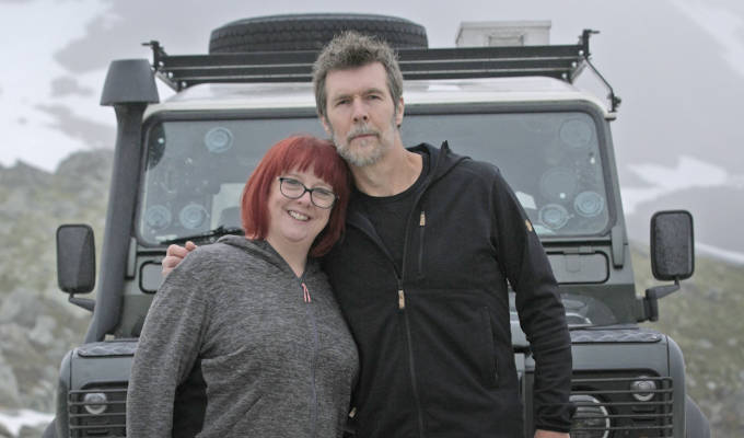 a man and a woman standing in front of a vehicle