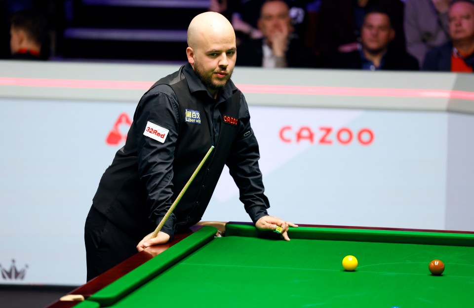 a man playing snooker in front of a cazoo sign