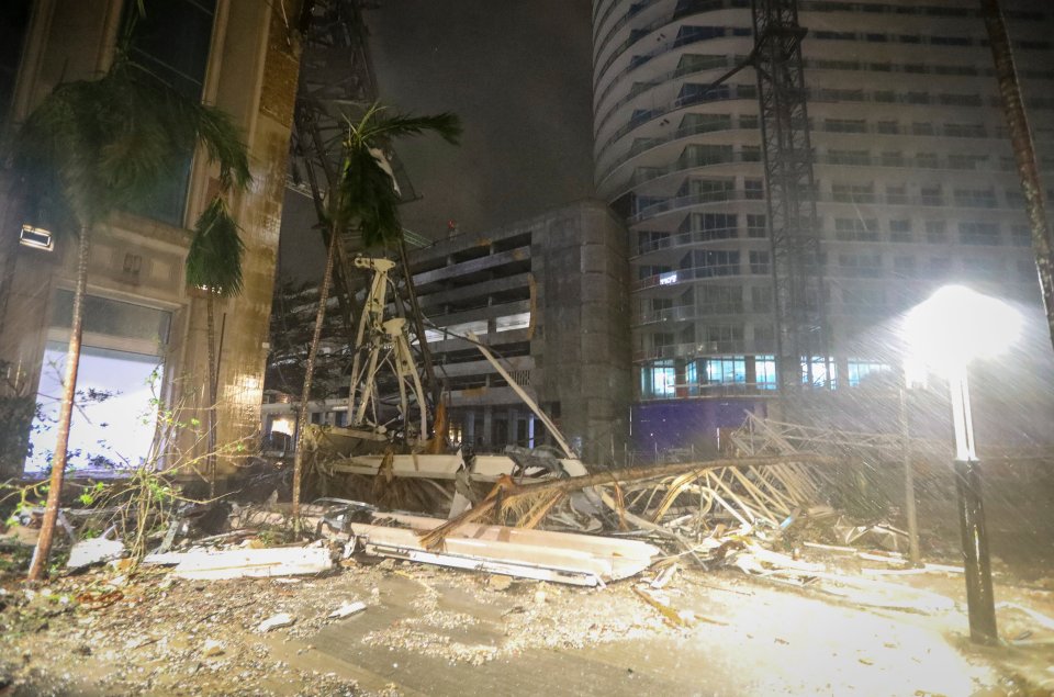 Debris covers the ground near a crane that fell onto a building along 1st Avenue South in St. Petersburg, as Hurricane Milton hit