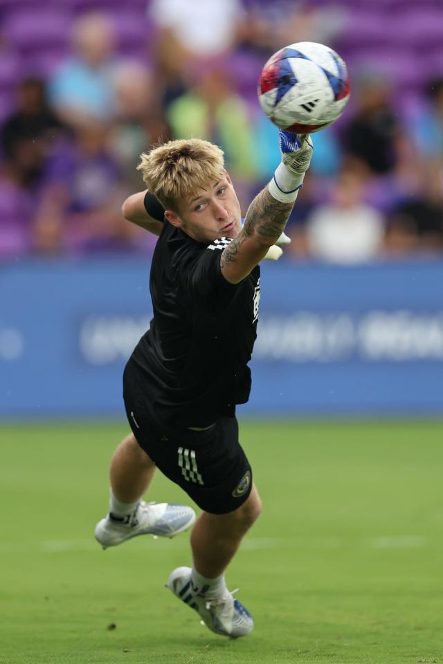 a soccer player with a tattoo on his arm catches a ball